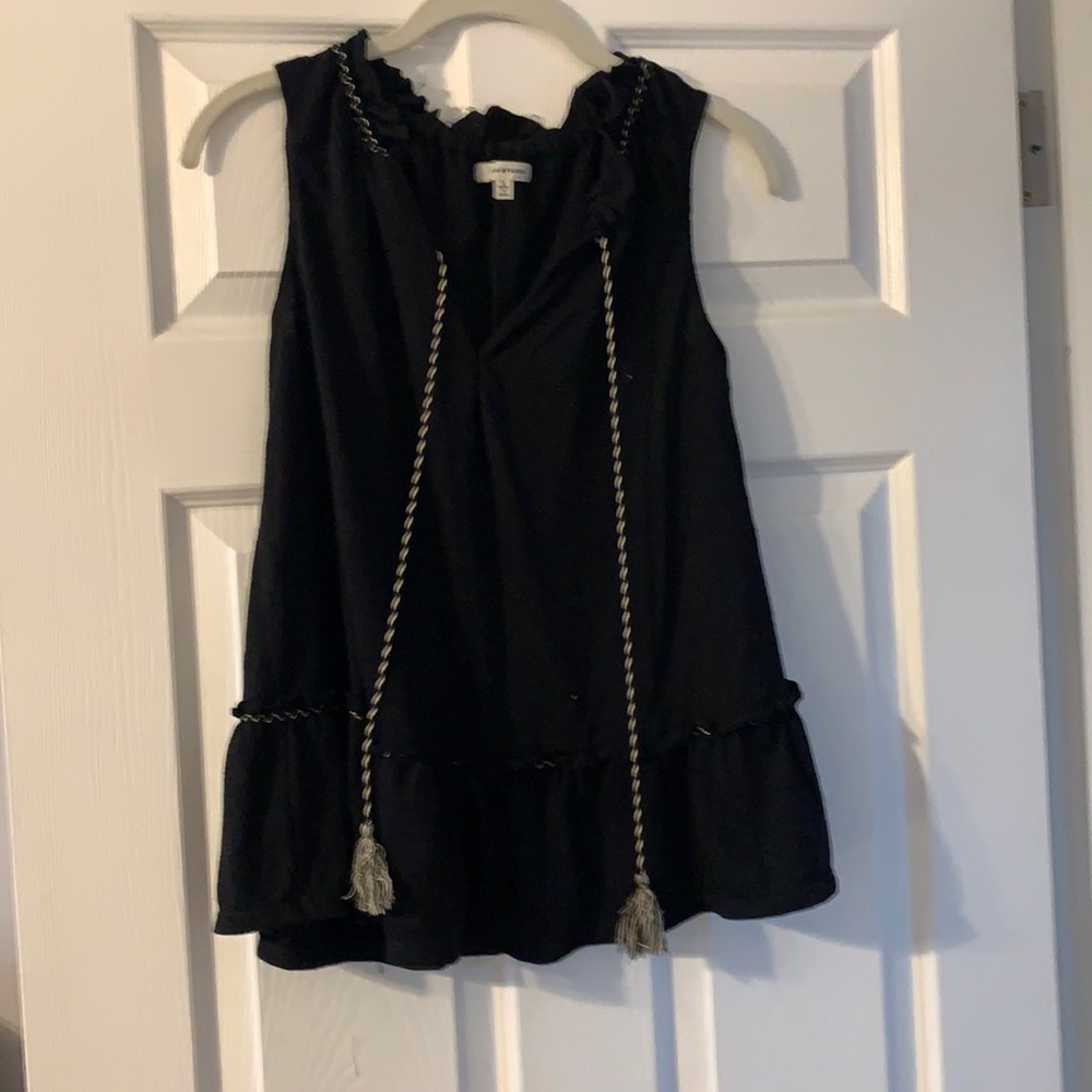 Black sleeveless top. Ruffle around the collar